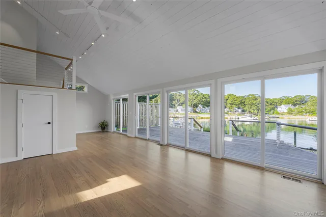 a view of empty room with wooden floor and fan