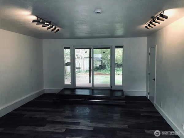 a view of an empty room with wooden floor and a window