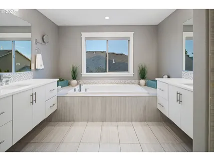 a spacious bathroom with a tub a double vanity sink a vanity and a window