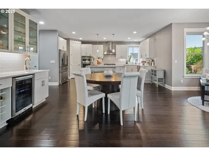 a kitchen with stainless steel appliances granite countertop a stove top oven a sink a dining table and chairs