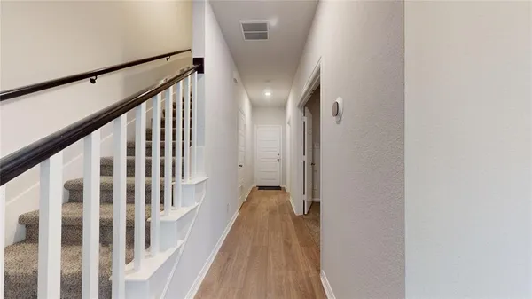 a view of a hallway with wooden floor and staircase
