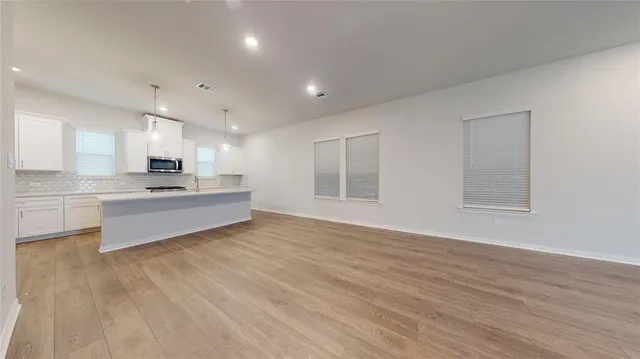 a large white kitchen with kitchen island a sink dishwasher a stove and a refrigerator with wooden floor