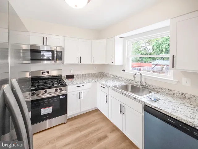 a kitchen with white cabinets appliances and a window