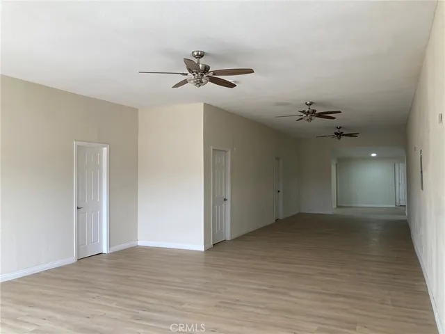 a view of a big room with wooden floor a ceiling fan and windows