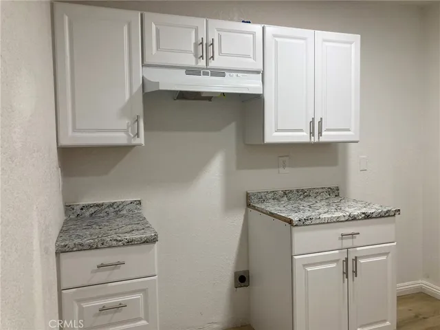 a kitchen with granite countertop white cabinets and a sink