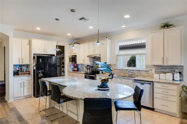 a kitchen with refrigerator a sink and chairs