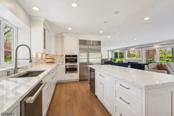 a large kitchen with stainless steel appliances granite countertop a lot of counter space and wooden floors