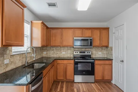 a kitchen with stainless steel appliances granite countertop a stove a sink and a microwave