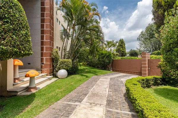 a view of a backyard with plants and brick wall