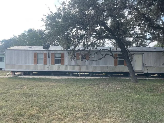 a view of a house with a yard and a large tree