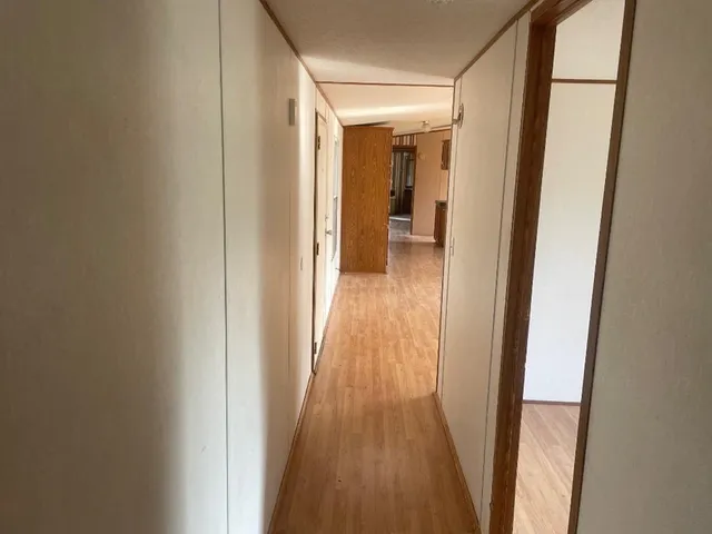 a view of a hallway with wooden floor and a bathroom
