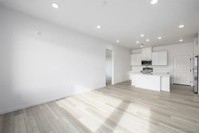 a view of kitchen with kitchen island sink refrigerator and white cabinets