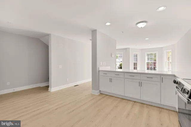 a large white kitchen with granite countertop a sink and dishwasher with wooden floor