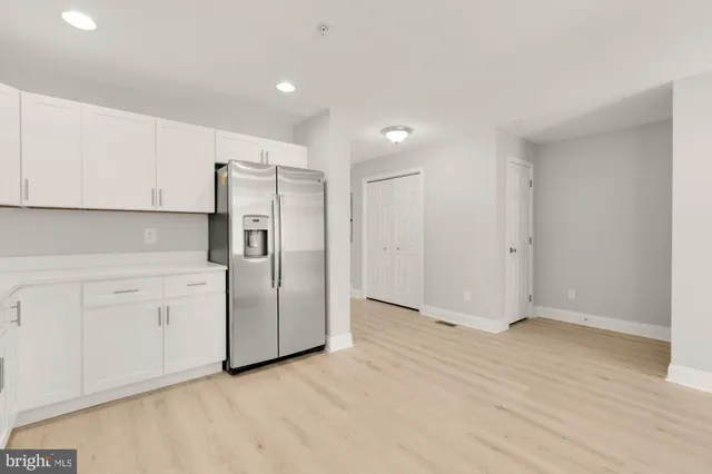 a view of a kitchen with refrigerator and white cabinets