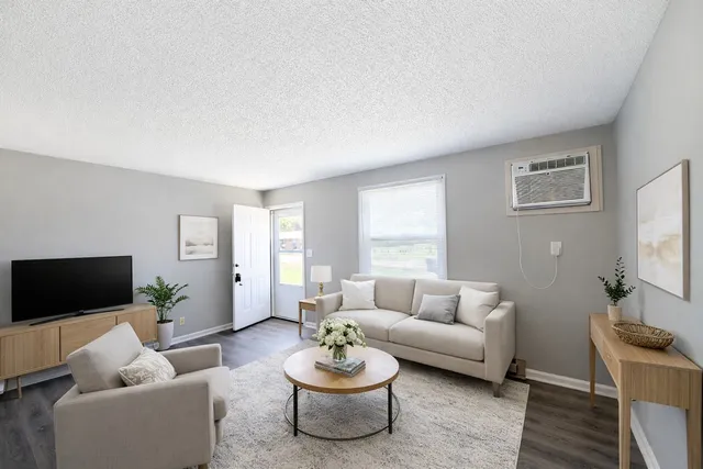 a living room with furniture a flat screen tv and a window