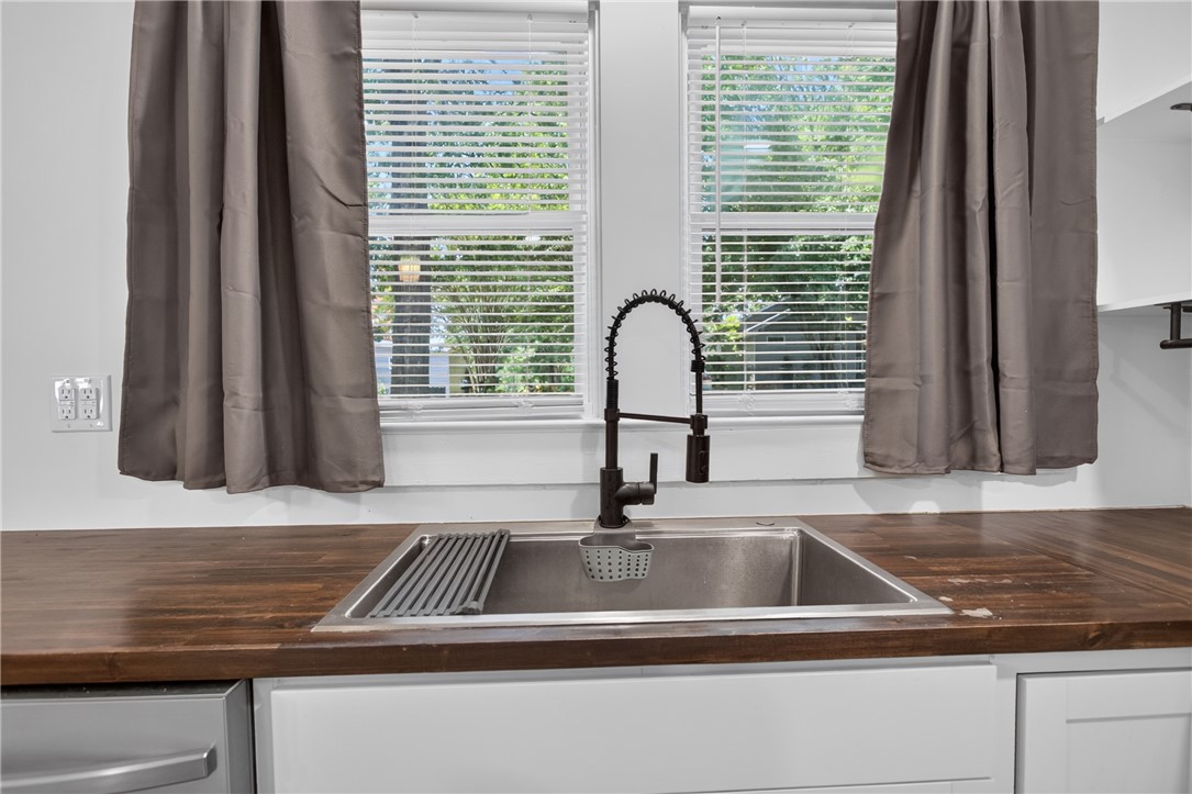 115 Pelfrey Street Seneca, SC 29672 - Photo 9 of 46 A well-appointed kitchen features a deep basin sink set into warm wood countertops, complemented by bright natural light.