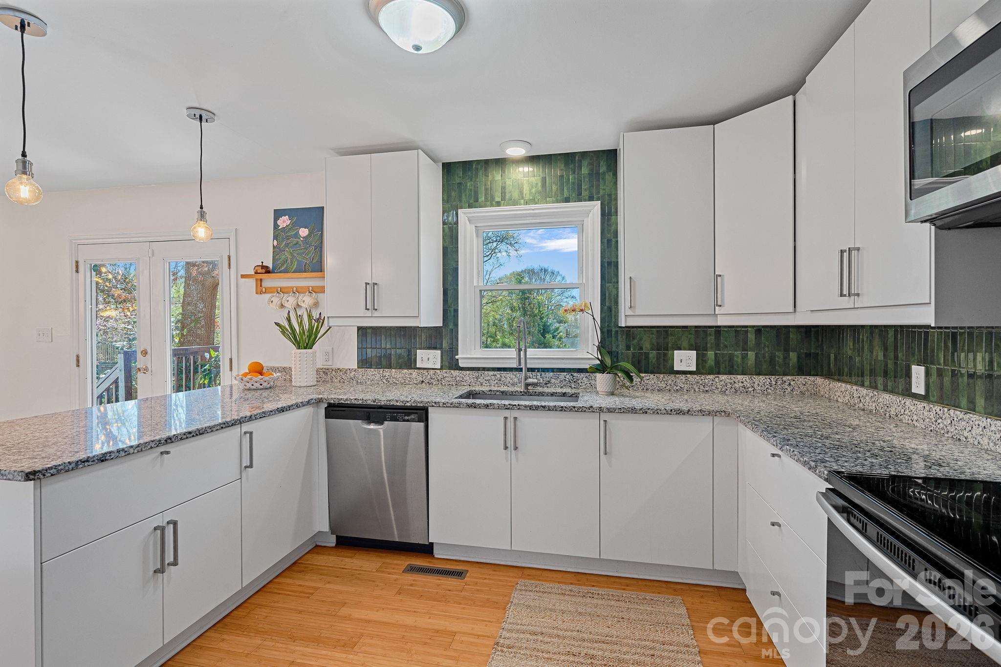 5236 Auburndale Road Charlotte, NC 28205 - Photo 6 of 26 a kitchen with stainless steel appliances granite countertop a stove a sink and a white cabinets with wooden floor