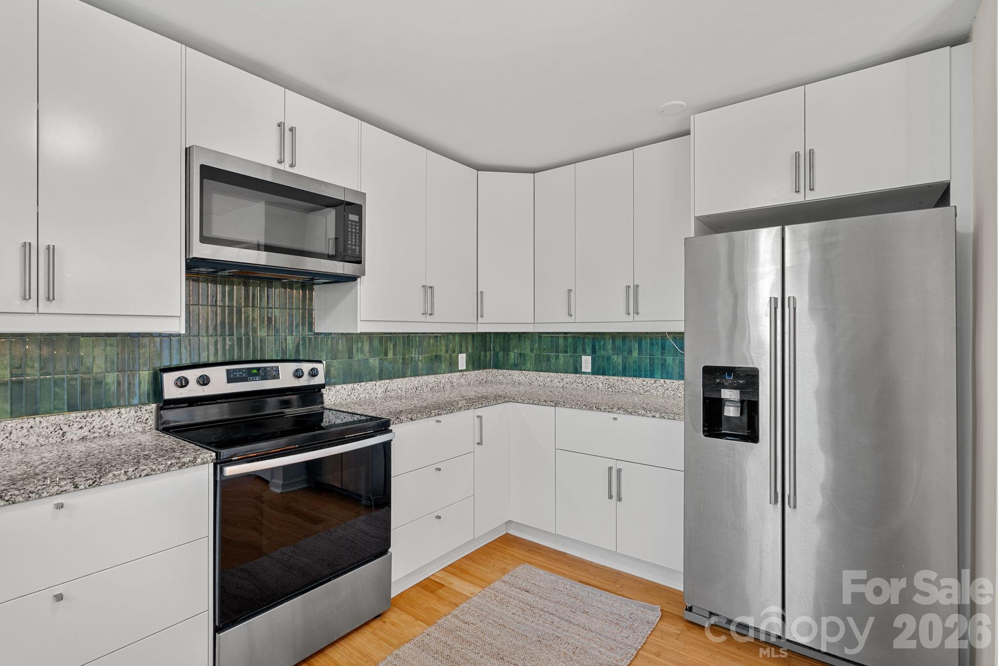 5236 Auburndale Road Charlotte, NC 28205 - Photo 7 of 26 a kitchen with stainless steel appliances white cabinets and a stove top oven