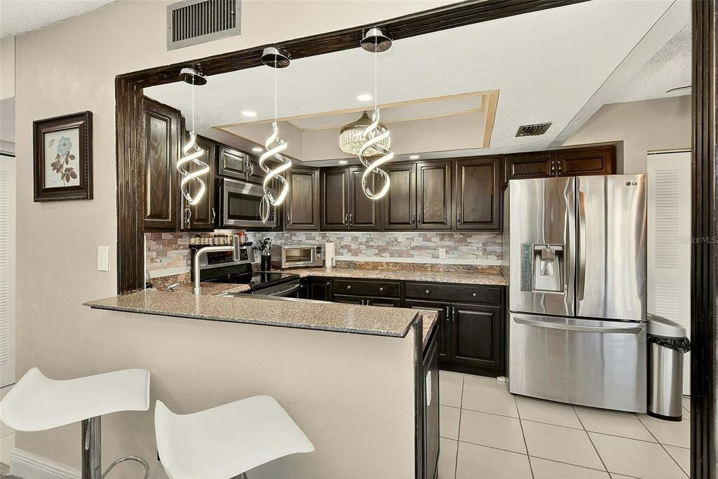 700 Starkey Road, Unit 1216 Largo, FL 33771 - Photo 6 of 32 a kitchen with stainless steel appliances granite countertop a refrigerator a stove and a sink