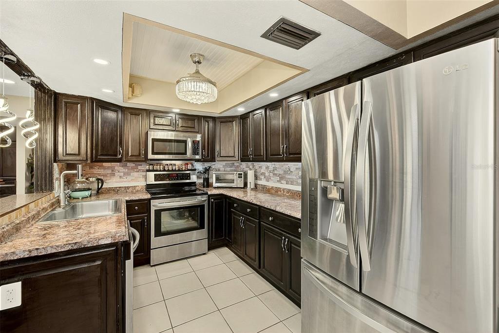 700 Starkey Road, Unit 1216 Largo, FL 33771 - Photo 7 of 32 a kitchen with granite countertop stainless steel appliances and wooden cabinets