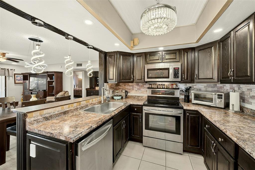 700 Starkey Road, Unit 1216 Largo, FL 33771 - Photo 8 of 32 a kitchen with stainless steel appliances granite countertop a stove microwave and cabinets