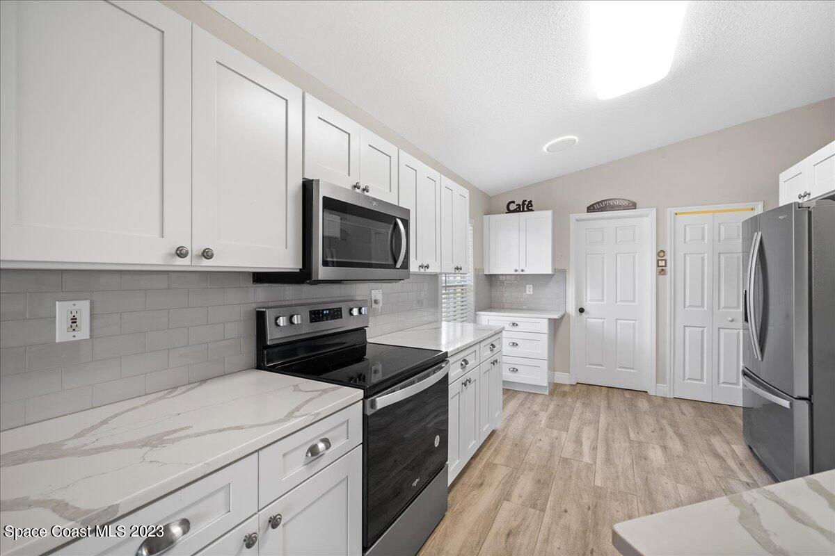 600 Benton Drive Melbourne, FL 32901 - Photo 11 of 33 a kitchen with a refrigerator a stove top oven and white cabinets