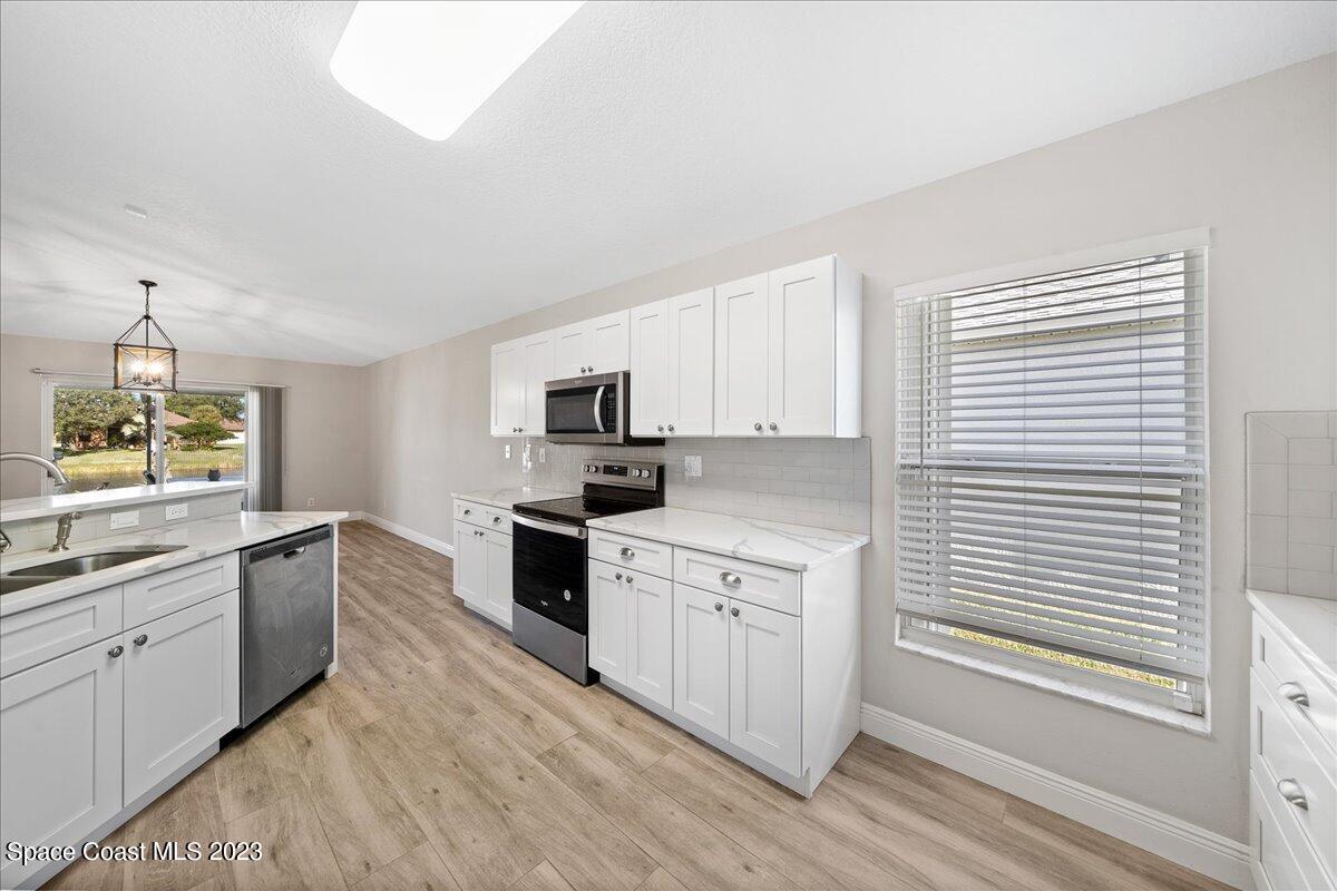 600 Benton Drive Melbourne, FL 32901 - Photo 12 of 33 a kitchen with granite countertop white cabinets and white appliances