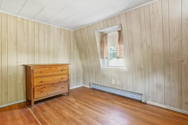 an empty room with wooden floor closet and windows