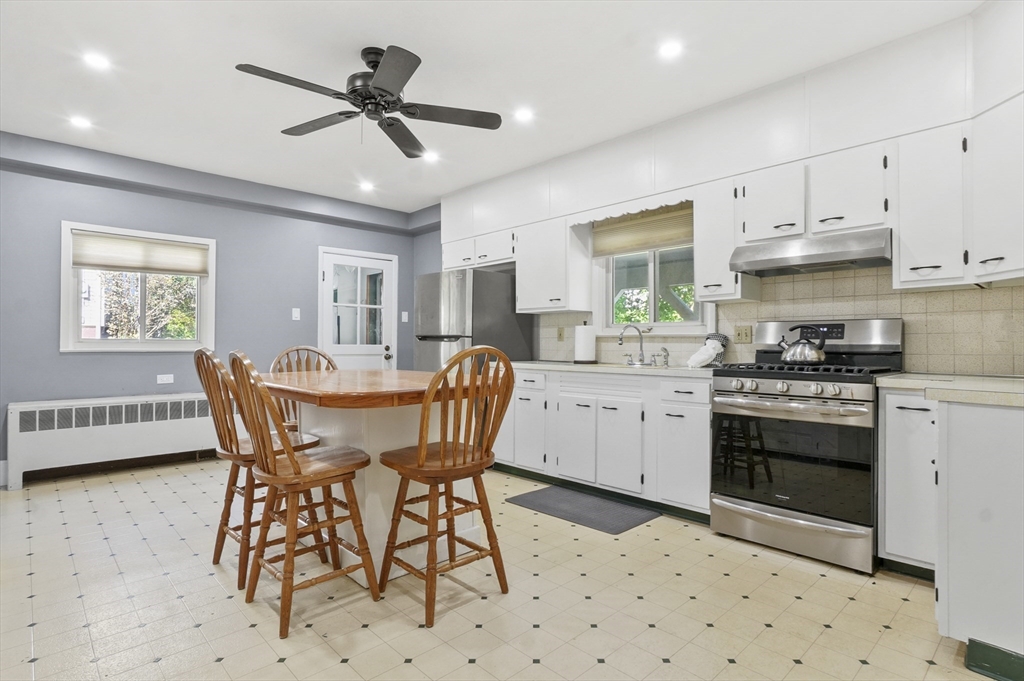 69 Eastern Avenue Woburn, MA 01801 - Photo 9 of 30 a kitchen with stainless steel appliances kitchen island granite countertop a sink a stove a dining table and chairs with wooden floor