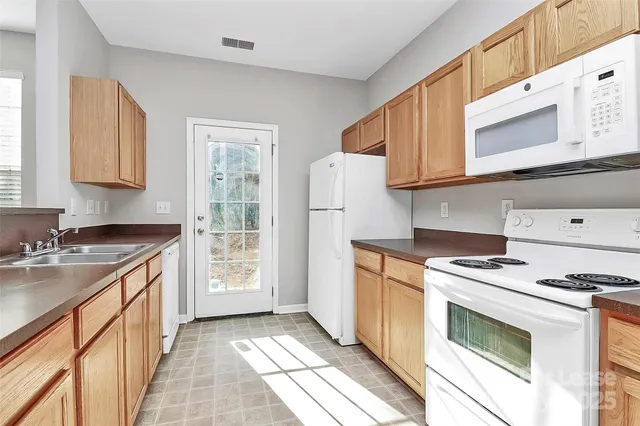 a kitchen with granite countertop a sink stove and refrigerator