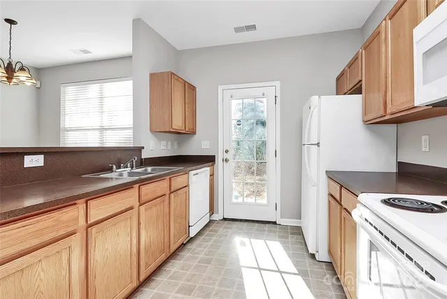 an empty room with chandelier fan and windows
