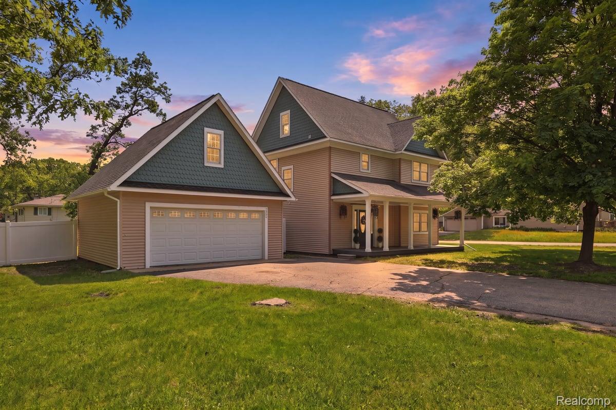 5685 Crescent Road Waterford, MI 48327 - Photo 1 of 47 Two-story residence featuring a covered front porch with white columns, light beige siding, and a gabled roofline with dark green shingles