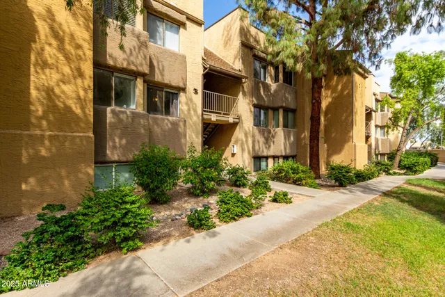 a front view of a multi story residential apartment building with yard and parking