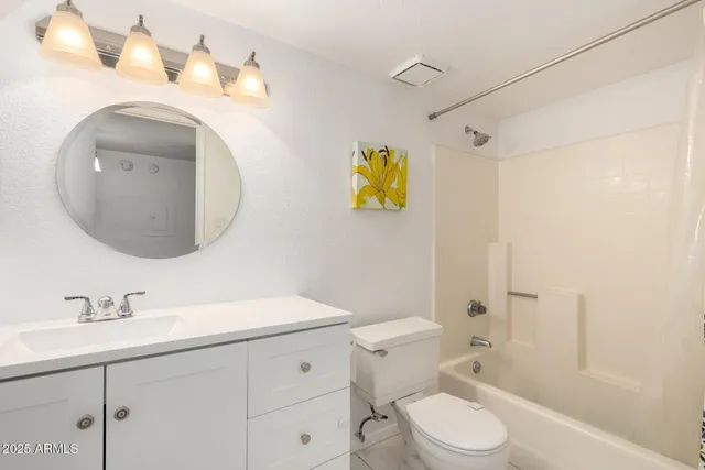 a bathroom with a toilet sink vanity granite and shower
