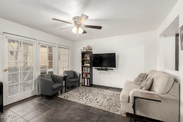 a living room with furniture a ceiling fan and a flat screen tv
