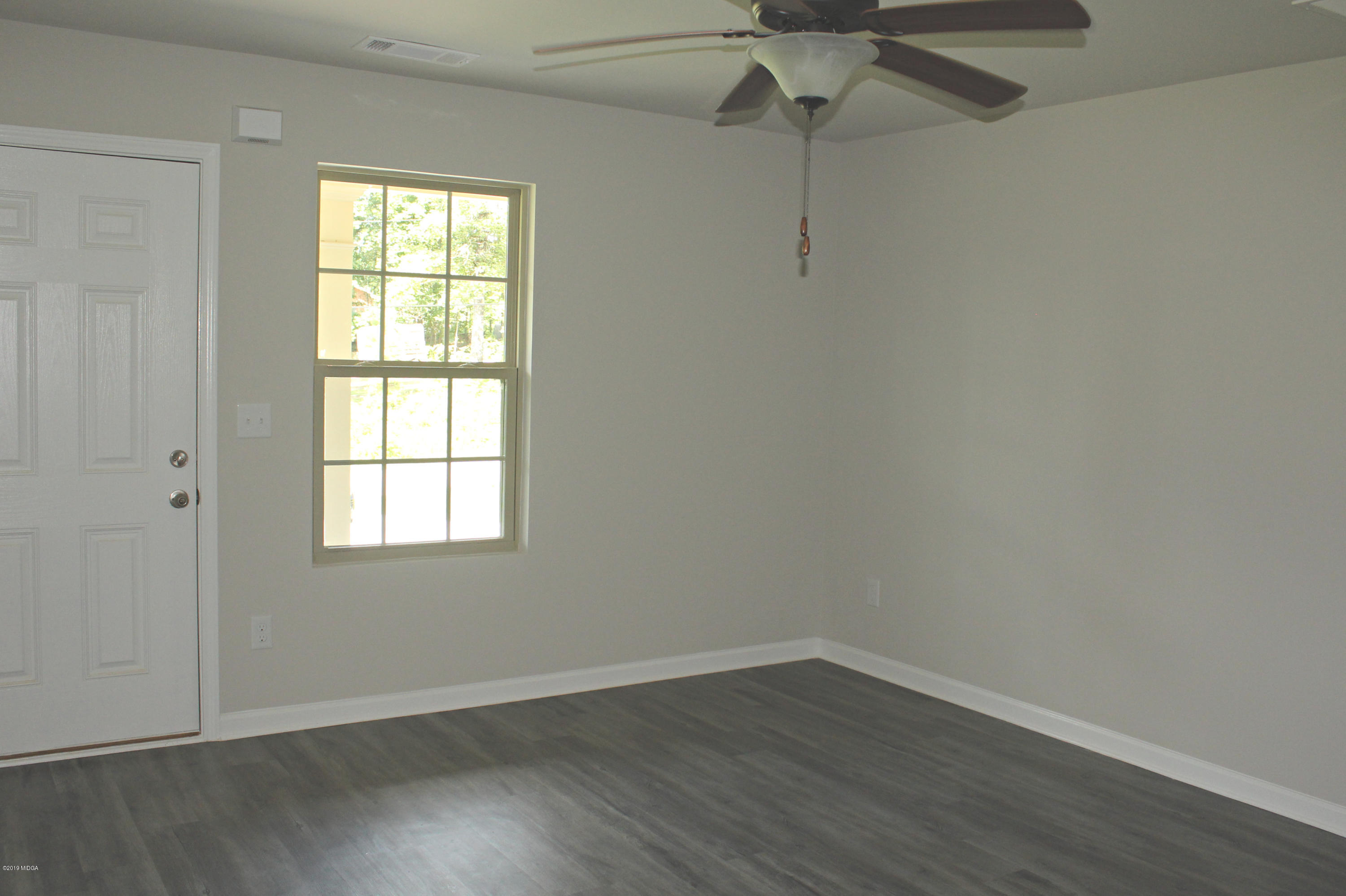 757 Weldon Road Forsyth, GA 31029 - Photo 2 of 8 an empty room with wooden floor closet and windows