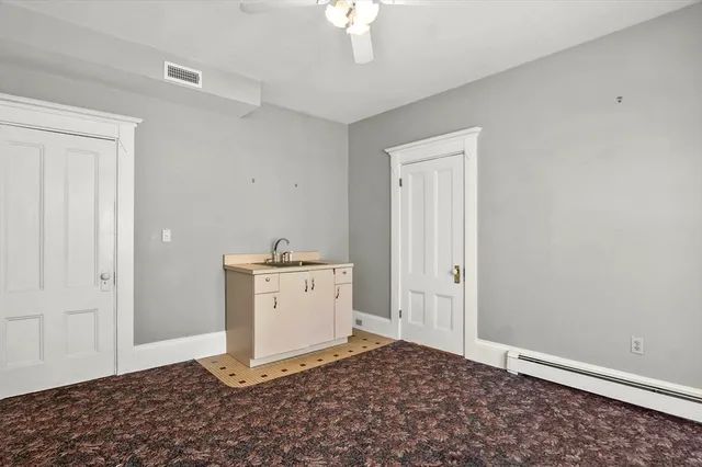a room with a chandelier fan and a window