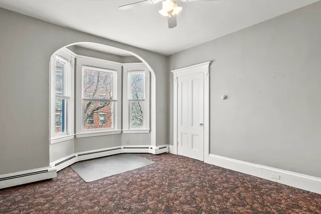 an empty room with windows and chandelier fan