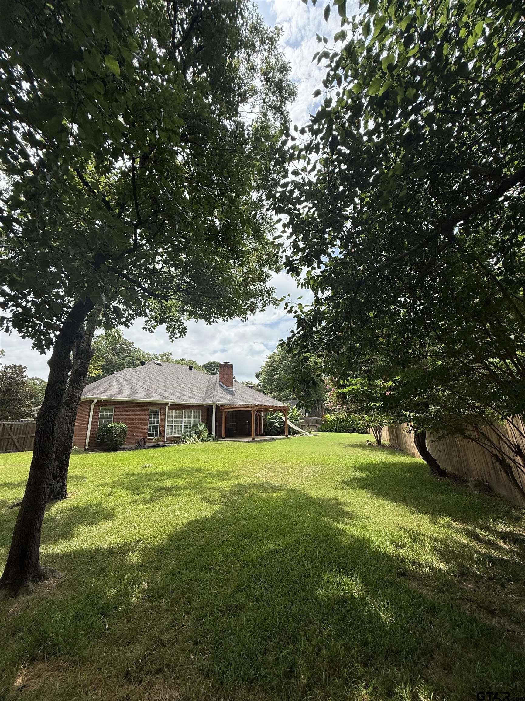 3204 Pebblebrook Circle Tyler, TX 75707 - Photo 16 of 18 a view of a house with a big yard and large trees