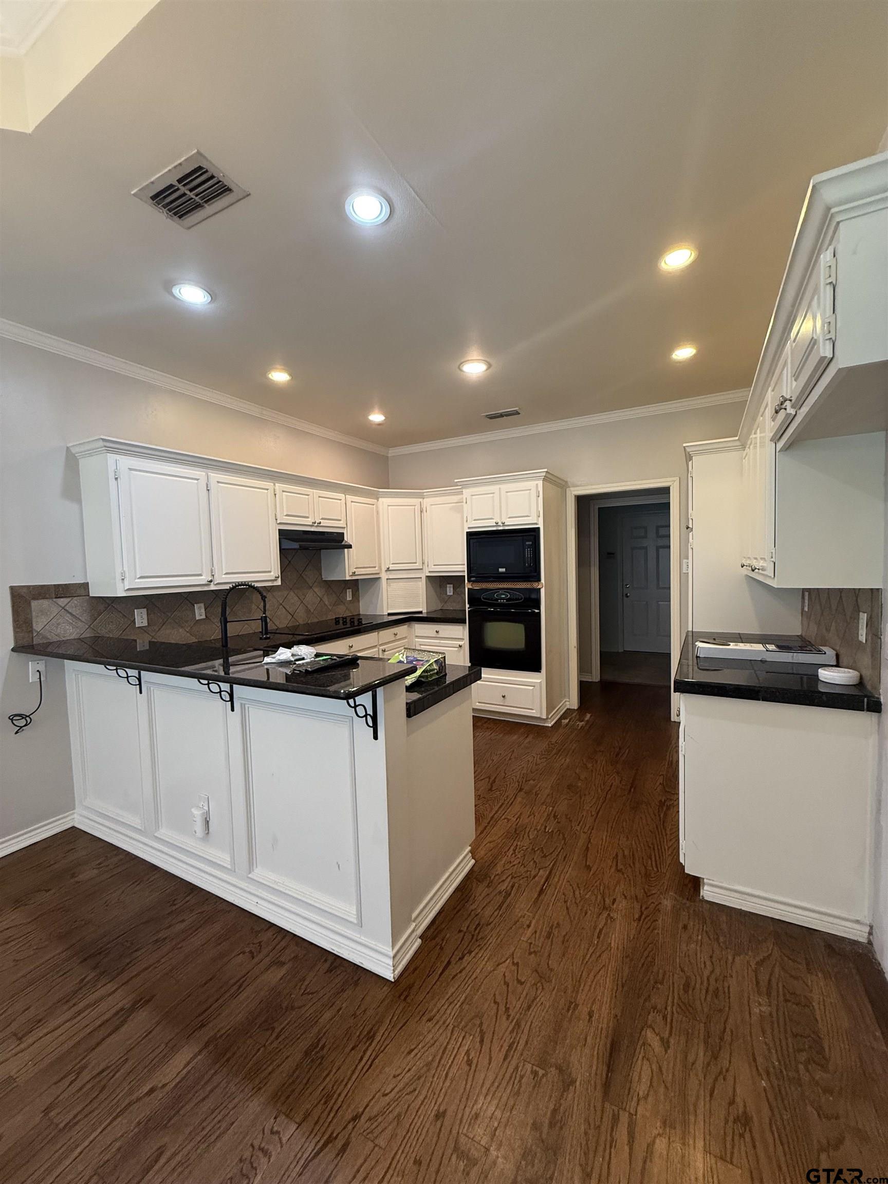 3204 Pebblebrook Circle Tyler, TX 75707 - Photo 3 of 18 a kitchen with stainless steel appliances granite countertop a stove top oven a sink a refrigerator and white cabinets with wooden floor