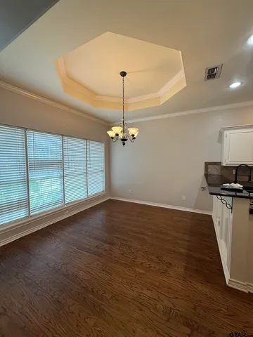 a view of a room with wooden floor ceiling fan and windows