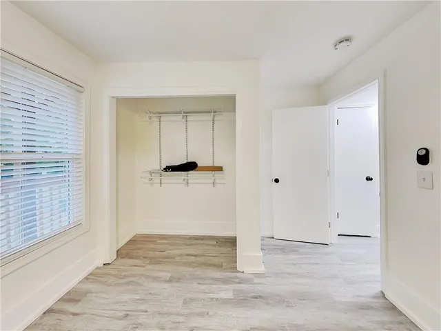 a view of a hallway with wooden floor and a bathroom