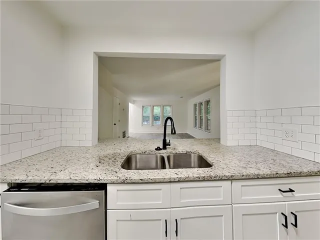 a kitchen with granite countertop a sink and a white wooden cabinets