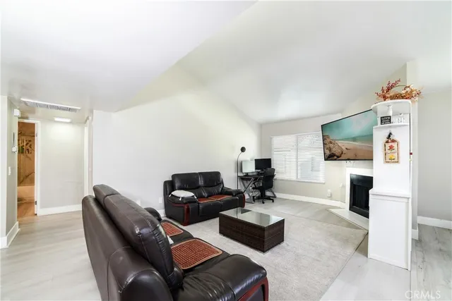 a living room with furniture a flat screen tv and a refrigerator