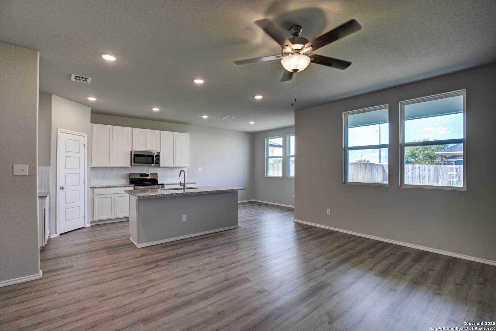 3453 Meteor Night Converse, TX 78109 - Photo 6 of 22 a large kitchen with stainless steel appliances granite countertop a large window a stove a sink dishwasher and a refrigerator with wooden floor
