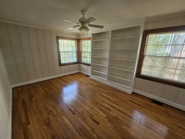 a view of an empty room with a window and wooden floor