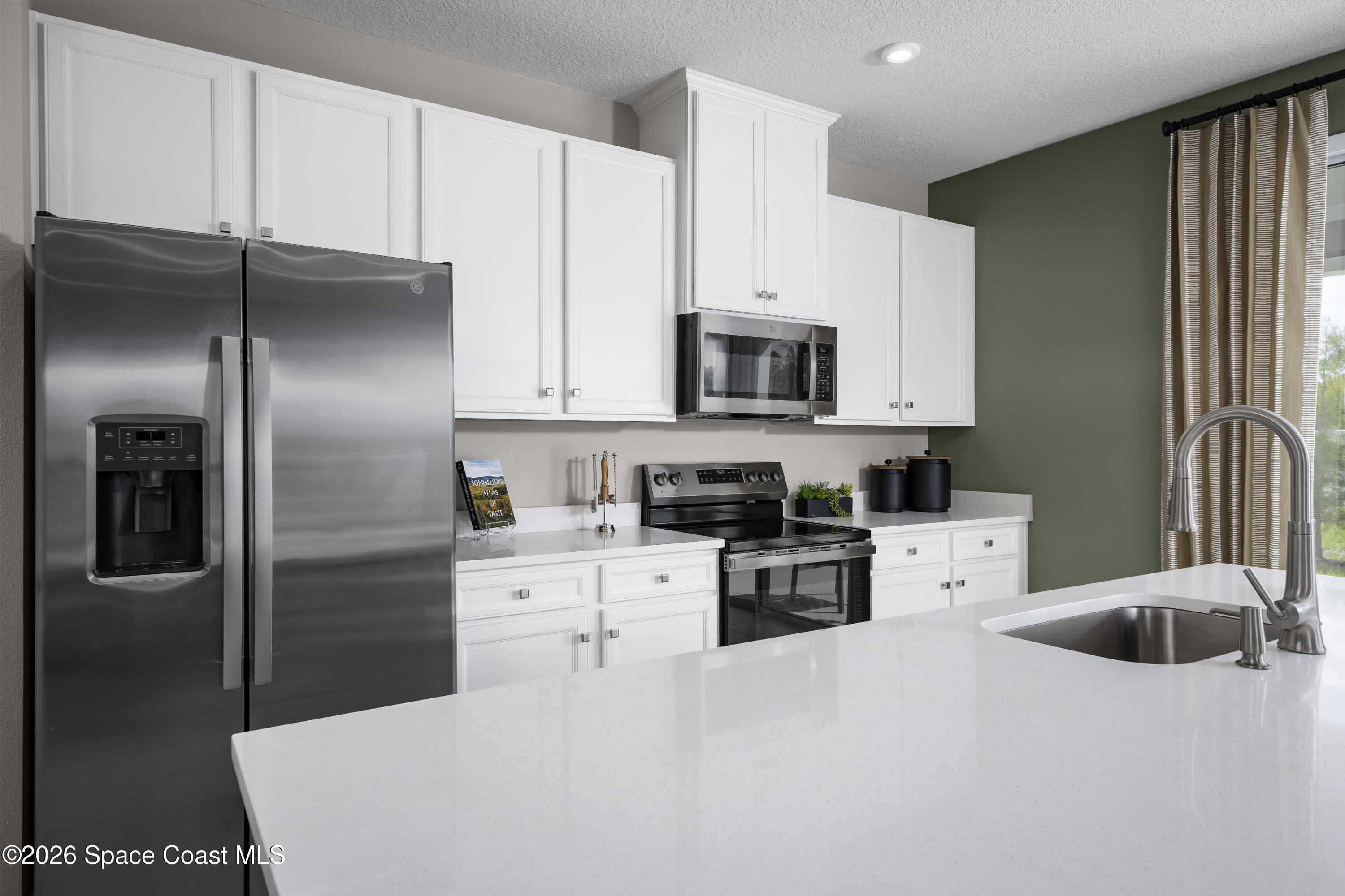 1758 Kendall Pointe Place Melbourne, FL 32935 - Photo 6 of 15 a kitchen with stainless steel appliances a refrigerator sink and white cabinets