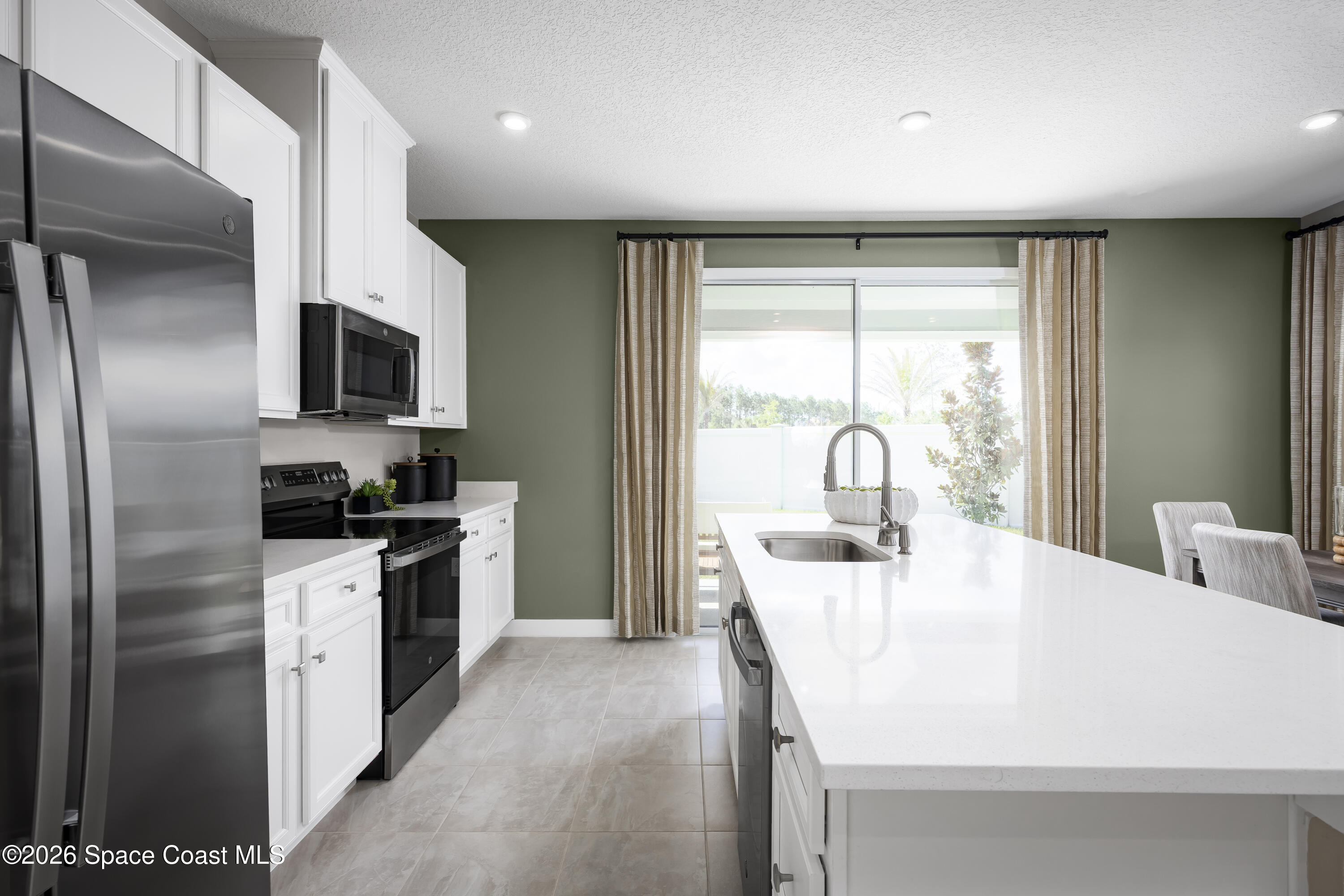 1758 Kendall Pointe Place Melbourne, FL 32935 - Photo 7 of 15 a kitchen with a sink a refrigerator and a stove top oven