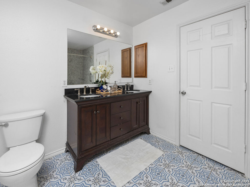 11031 Rindle Ranch San Antonio, TX 78249 - Photo 30 of 45 a bathroom with a toilet sink vanity and mirror
