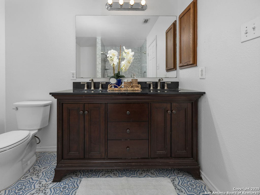 11031 Rindle Ranch San Antonio, TX 78249 - Photo 31 of 45 a bathroom with a toilet a sink and a mirror